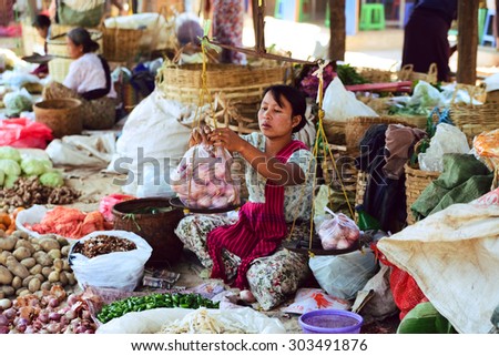 INLE LAKE, MYANMAR, FEB 29, 2015: An ethnic minority woman sell vegetable in a traditional market. There are 8 ethnic minority group in Inle lake area