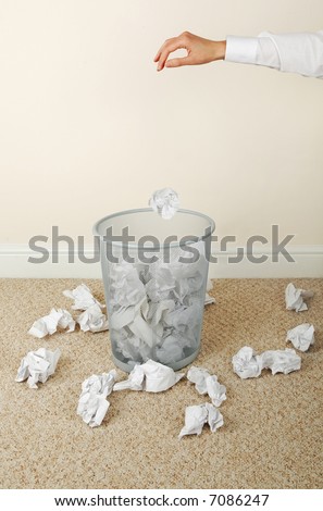 Woman throwing paper in waste paper bin, close-up of hand