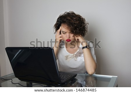 Stressed business woman, working at her desk, with a headache, holding head with both  hands, isolated, studio shoot.