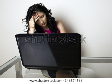Stressed business woman working at her desk, holding head with right hand, isolated, studio shoot.