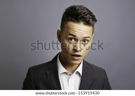 Surprised man in formal wear, eyes open wide, open mouth, raised eyebrows, amaze expression, head and shoulders, studio shoot.