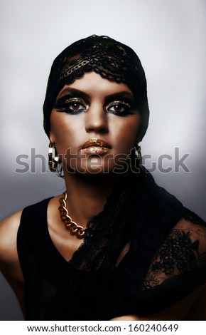Sensual woman with black veil, artistic print, black and gold, jewelry, gypsy style, make-up art,elegance and mystery,  icon, gray background.