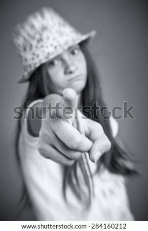 Blurred Portrait of sad girl pointing. Focus on the fingertip.
