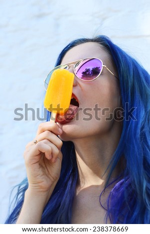Young sexy punk girl eating yellow ice cream in summer hot weather in round  pink sunglasses