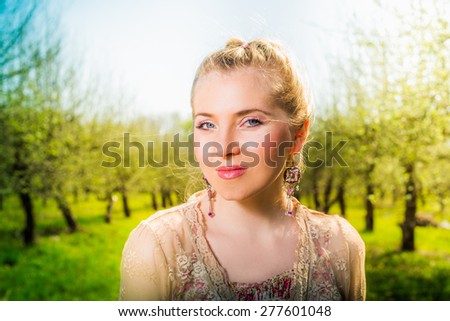 Beautiful young blonde woman standing near the apple tree in garden park outdoor