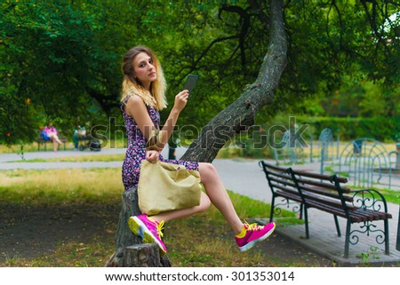 Young woman using tablet outdoor sitting on tree, weird, smile.