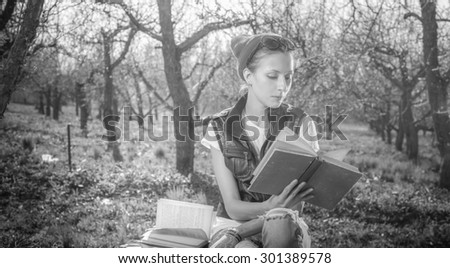 Black and White, BW. Woman in park outdoor with tablet and paper book deciding what to use