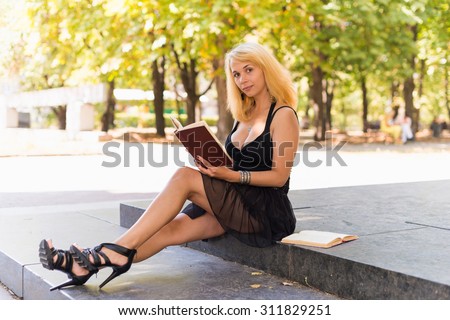 Image of young beautiful woman in summer park reading a book