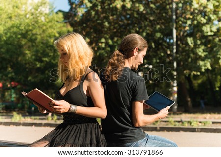 Couple using tablet and reading paper book