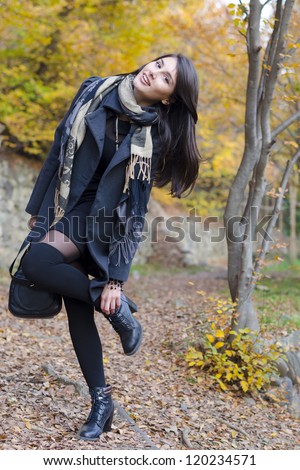 Happy woman, adjusting her shoes in the autumn forest