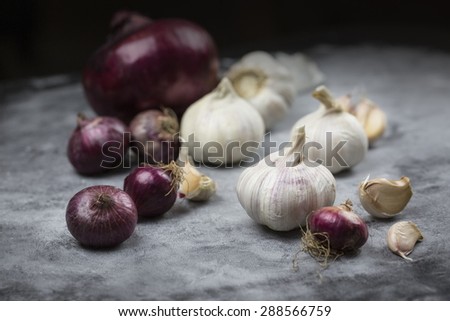 Whole organic garlic and red bulb onions on wooden table