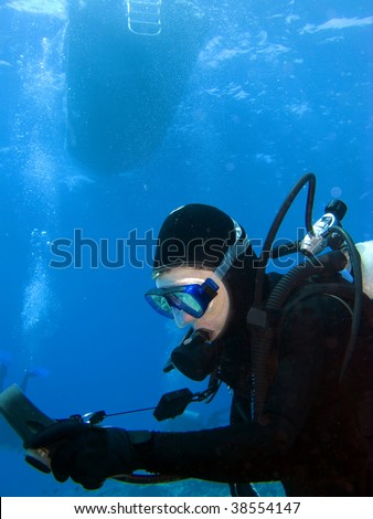 Female Scuba Diver checking Gauges under the Boat