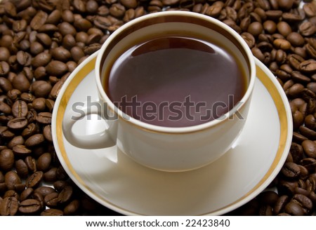 Cup with hot coffee on a coffee beans background. Shallow DOF. Focus on coffee beans