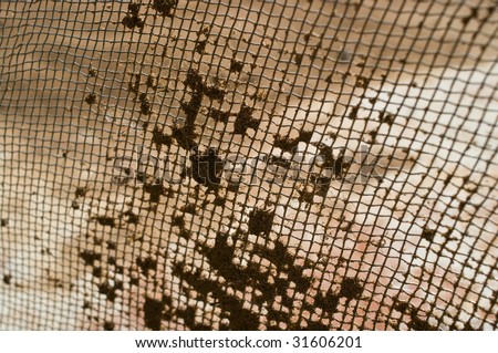 Building sieve with the stuck sand. An abstract background