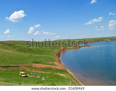 The family has arrived on picnic to lake. Summer landscape with the cloudy sky. Hills of the Ural mountains and blue lake.