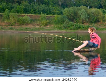 The girl-fisher sits on a log in the middle of the river. Summer landscape