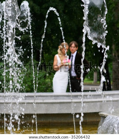 bride and groom in summer park. Shallow DOF, focus on fountain