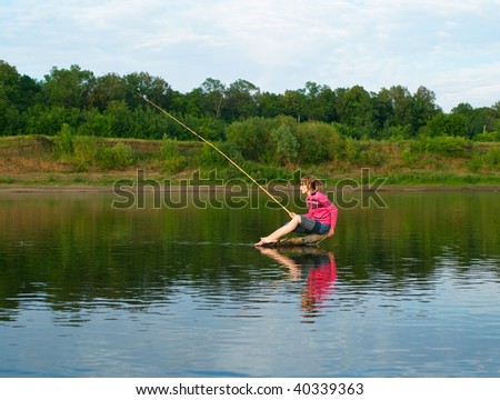 The girl-fisher sits on a log in the middle of the river. Summer landscape