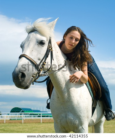 The serenity young girl astride a horse against blue sky. Shallow DOF, focus on a muzzle of a horse