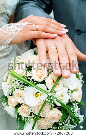 Hands of a newly-married couple on flower bouquet