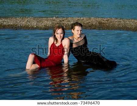 Beautiful young girls in wet dress sits in water of the river