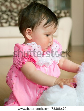 Beautiful little baby in pink dress with toy at home. Shallow DOF