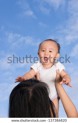 picture of mom lifting baby with blue sky as background taken outdoor
