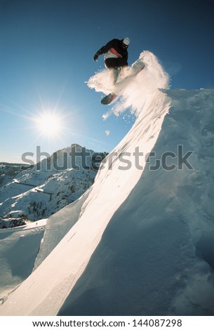 Snowboarding off a cliff off piste on a sunny day in Donner Pass, California, USA