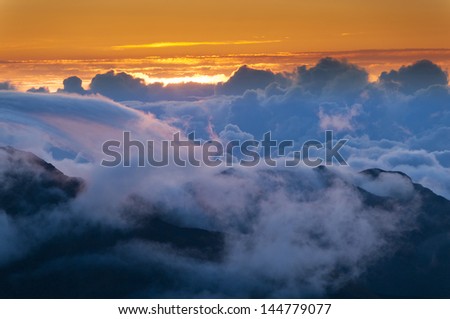 Sun rising over clouds at sunrise from on top of Haleakala Crater, Maui, Hawaii, USA