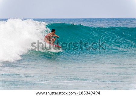 KOLOA, KAUAI, HI - APRIL 24, 2008 - Young man riding a boogie board in a blue wave in the summer.