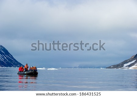HORNSUND, SVALBARD, NORWAY - JULY 26,  2010: Tourists from the National Geographic Explorer cruise ship on inflatable rafts in the Artic Ocean exploring a fijord in the Arctic.