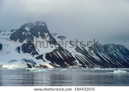 HORNSUND, SVALBARD, NORWAY - JULY 26, 2010:  National Geographic Explorer cruise ship in front of a glacier in the Arctic Ocean.