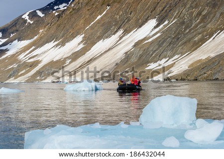HORNSUND, SVALBARD, NORWAY - JULY 26, 2010: Tourists from the National Geographic Explorer cruise ship on inflatable rafts in the Artic Ocean exploring a fijord in the Arctic.