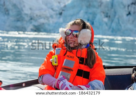 HORNSUND, SVALBARD, NORWAY - JULY 26, 2010: Young girls from the National Geographic Explorer cruise ship playing with salt water ice from the Arctic Ocean.