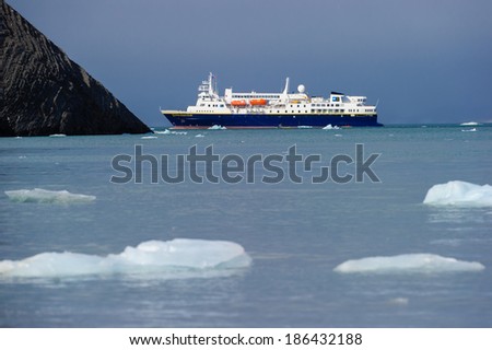 HORNSUND, SVALBARD, NORWAY - JULY 26, 2010:  National Geographic Explorer cruise ship in front of a glacier in the Arctic Ocean.