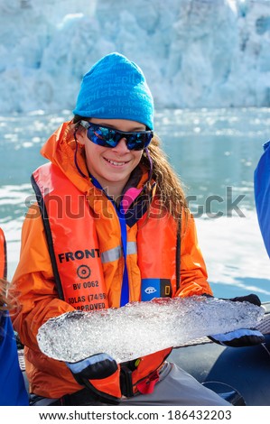 HORNSUND, SVALBARD, NORWAY - JULY 26, 2010: Young girls from the National Geographic Explorer cruise ship playing with salt water ice from the Arctic Ocean.