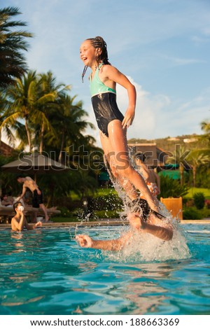 Younger girl jumping off of an older girls shoulder while swimming in a pool, Cruz Bay, St. John, USVI