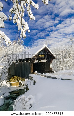 Emily\'s Covered Bridge blanketed in fresh snow on a sunny winter morning, Stowe, Vermont, USA