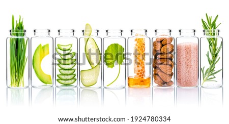 Homemade skin care with natural ingredients wheat grass ,avocado ,aloe vera ,cucumber ,himalayan salt  ,honeycomb ,almonds, centella asiatica and rosemary  in glass bottles isolate on white background