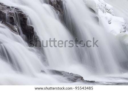 Winter, Bond Falls cascade captured with motion blur and framed by ice and snow, Michigan\'s Upper Peninsula, USA