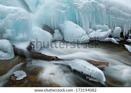 Winter landscape of cascade captured with motion blur and framed by blue ice, Gull Creek, Michigan, USA