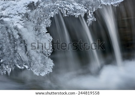 Winter Orangeville Creek cascade framed with icicles and captured with motion blur, Michigan, USA