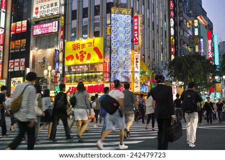 SHINJUKU, TOKYO - MAY 31, 2014: Street view of Shinjuku commercial district at night, billboards with neon light and crowd of pedestrians.