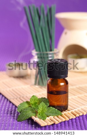 Bottle of essential oil, mint leaves and candles. Let\'s go spa!