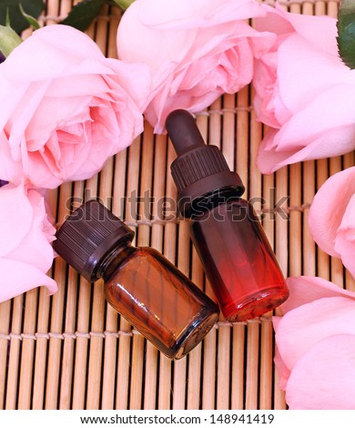 Two bottles essential oil and rose flowers on bamboo mat, come on, let\'s go spa.