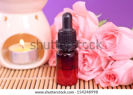 One bottle of essential oil and rose flowers on bamboo mat, come on, let\'s go spa.