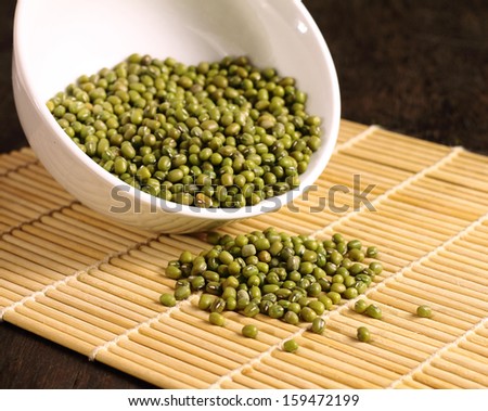Bowl of dried green beans on yellow bamboo mat background