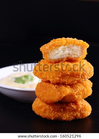 A pile of chicken nuggets on black color background with sauce