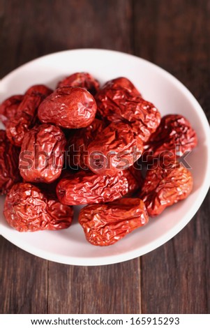 Dried chinese jujubes fruits with white plate on wooden table