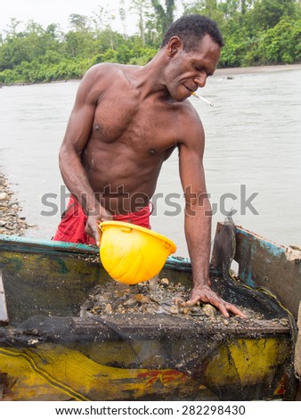The Jungle, Indonesia - January 20, 2015: A man from the Korowaya tribe washing out gold using a bowl